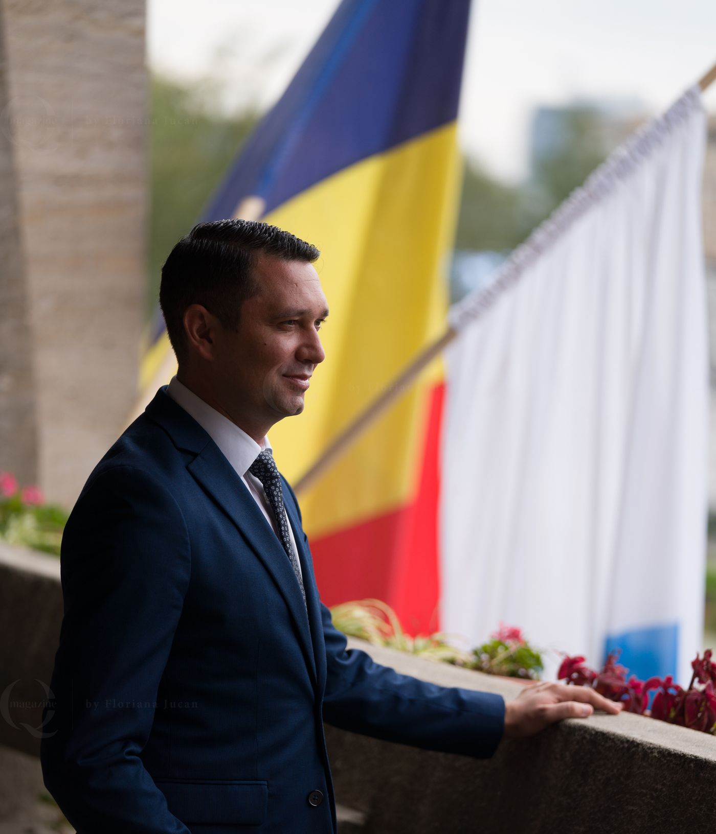 Bogdan Toader, în costum, lângă drapelul României